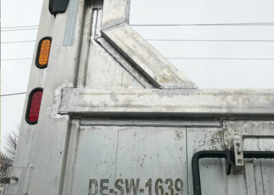 Closeup view of the back of a 3 axle dump truck showing repairs done on the dump box
