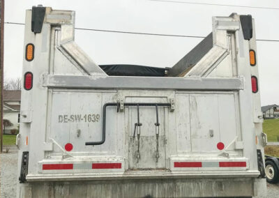 Back view of a 3 axle dump truck with a repaired dump box