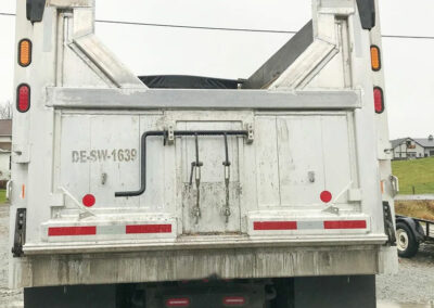 Back view of a 3 axle dump truck with a repaired dump box