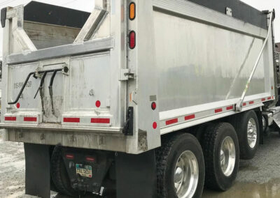 Side and back view of a 3 axle dump truck with a repaired dump box