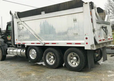 side view of a 3 axle dump truck with a repaired dump box