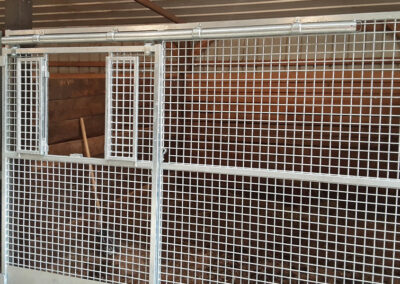 Close up view of a horse stall with a metal mesh front gate