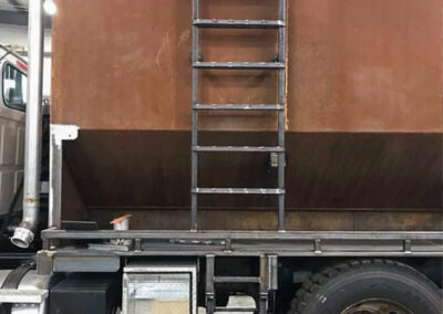 Customized metal ladder welded to the side of a commercial truck.