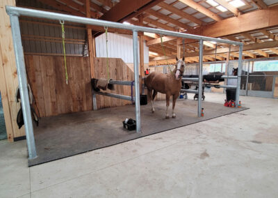 Horse tethered to a custom metal rail in a large stable