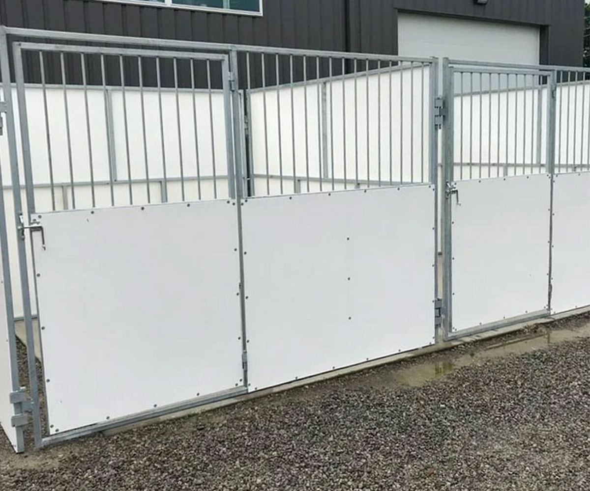 Portable horse stall panels set up outside a barn.
