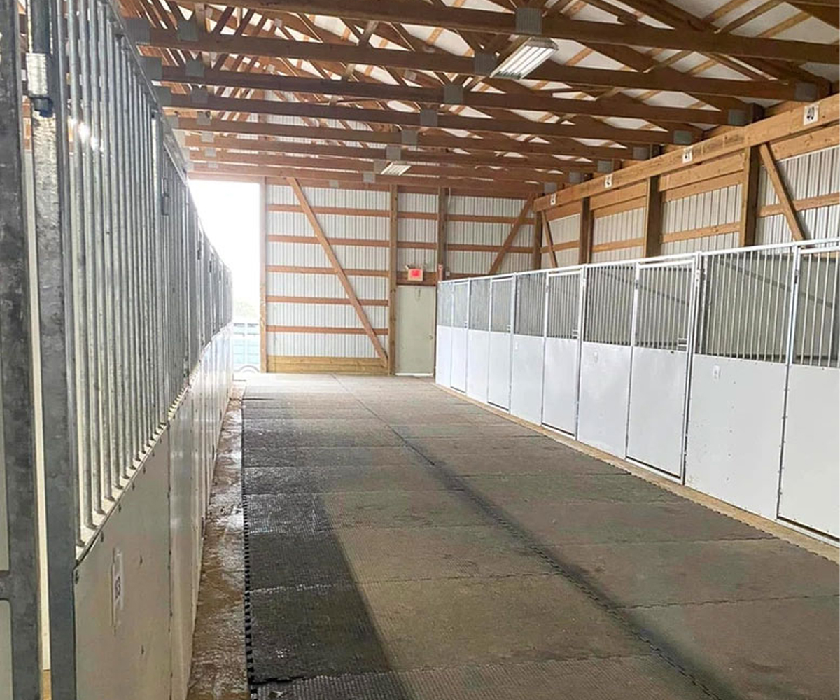 Rows of portable horse stalls inside a large indoor arena.